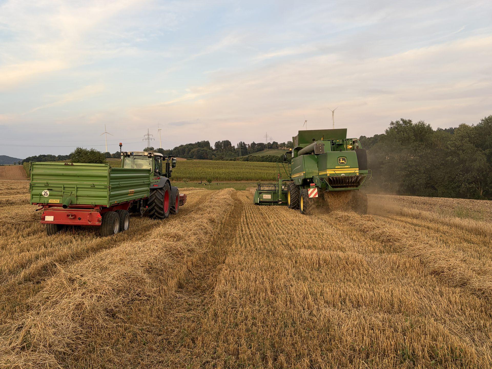 Traktor mit Anhänger und Mähdrescher auf dem Stoppelfeld