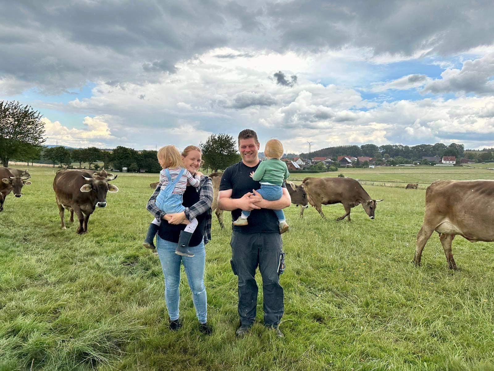 Martin und Janina Koch mit Mathilda und Emil auf der Weide zwischen Braunvieh-Kühen