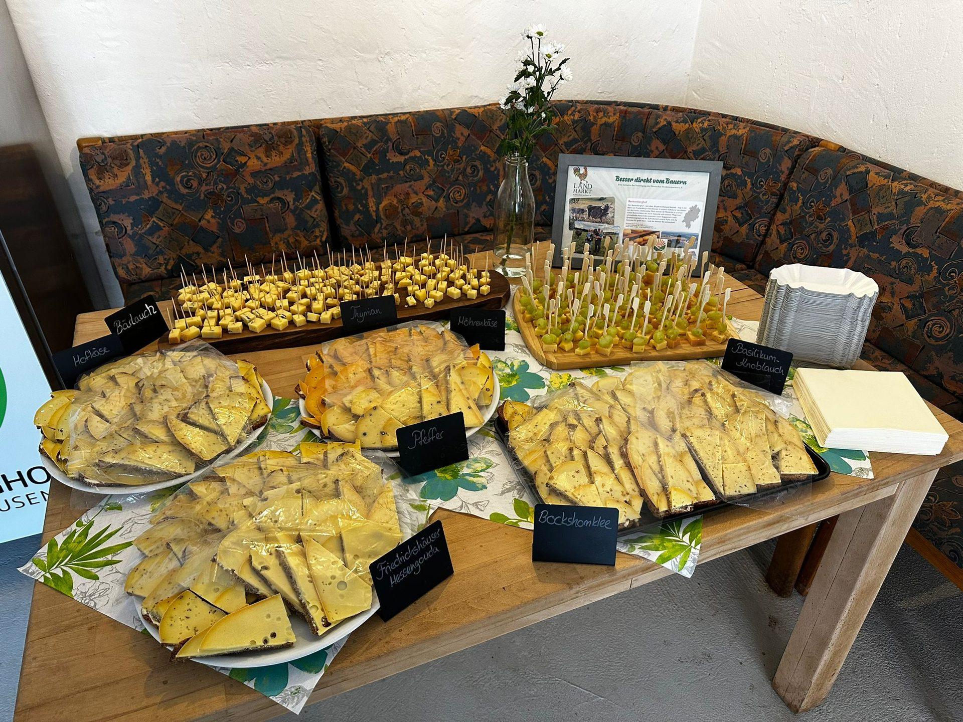Käsebuffet mit beschrifteten Sorten: Hofkäse, Bärlauch, Thymian, Möhrenkäse, Pfeffer, Friedrichshäuser Hessengouda, Bockshornklee und Basilikum-Knoblauch