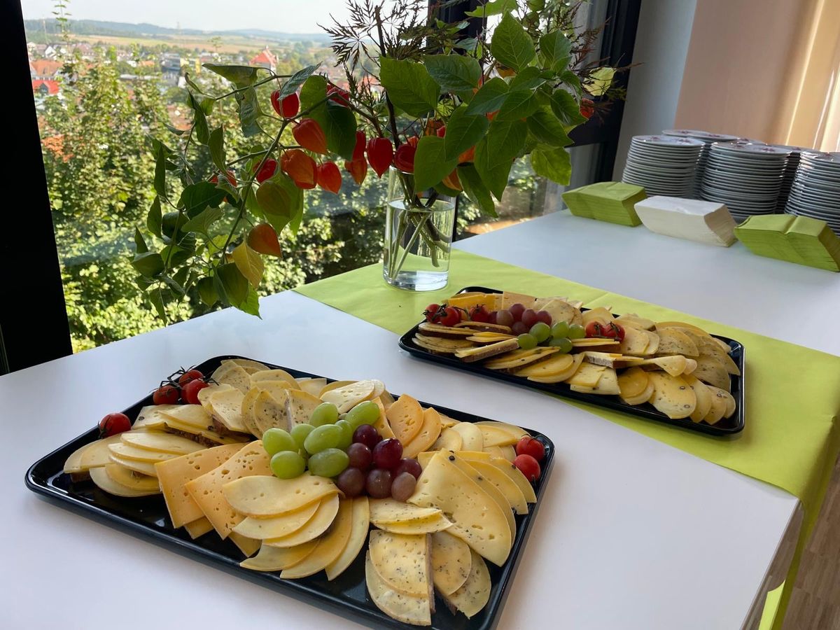 Zwei angerichtete Käseplatten mit Käsescheiben, Trauben und Beeren auf einem Tisch